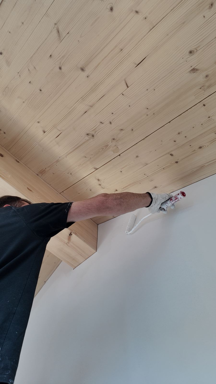 Präziser Anstrich an der Kante zwischen Wand und Holzdecke
