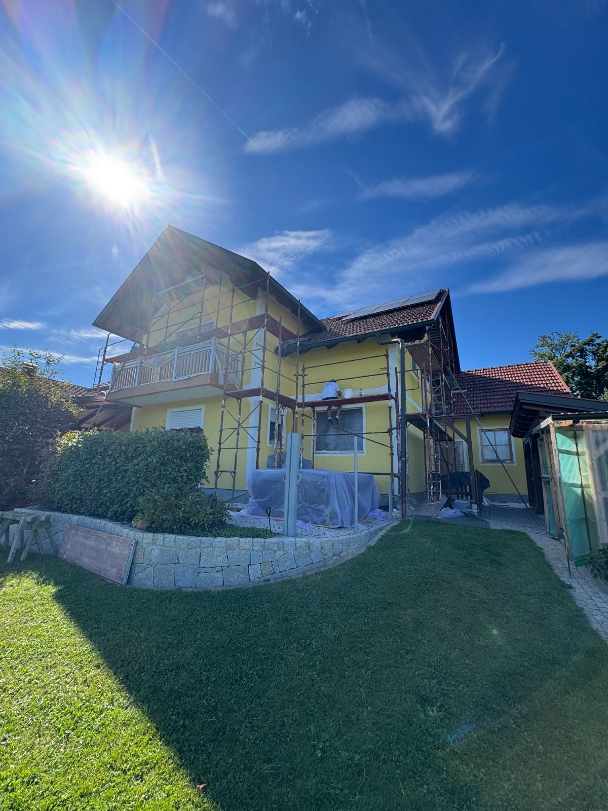 Eingerüstetes gelbes Wohnhaus bei Sonnenschein