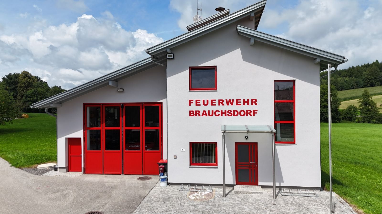 Feuerwehrhaus mit neu gestrichener weißer Fassade und roten Toren