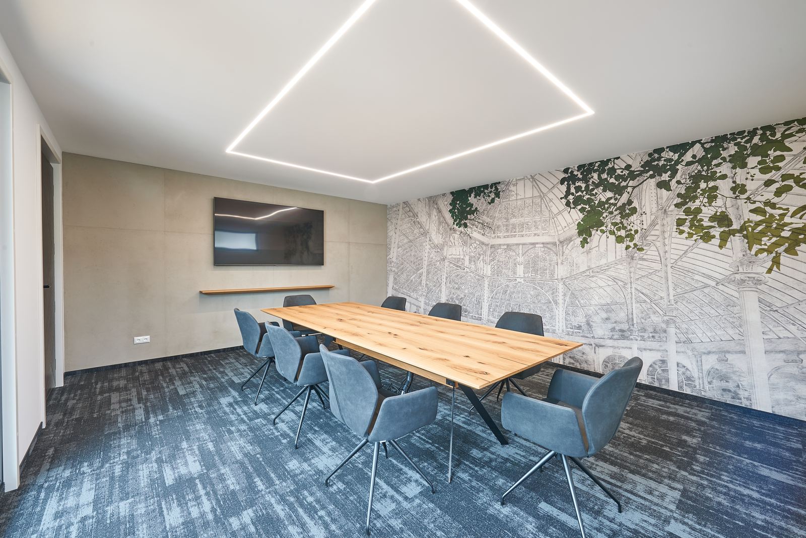 Heller Besprechungsraum mit Wintergarten-Wandbild, Betonoptik-Wand und Lichtrahmen an der Decke