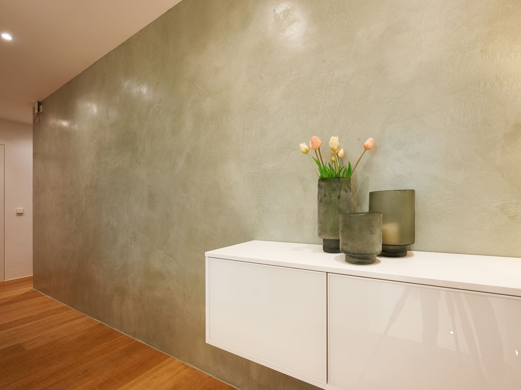 Mineralische grüne Wandoberfläche mit Sideboard und Blumen