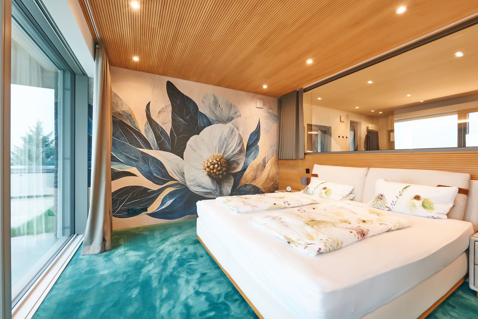 Schlafzimmer mit großem Magnolien-Wandbild und türkisem Teppich