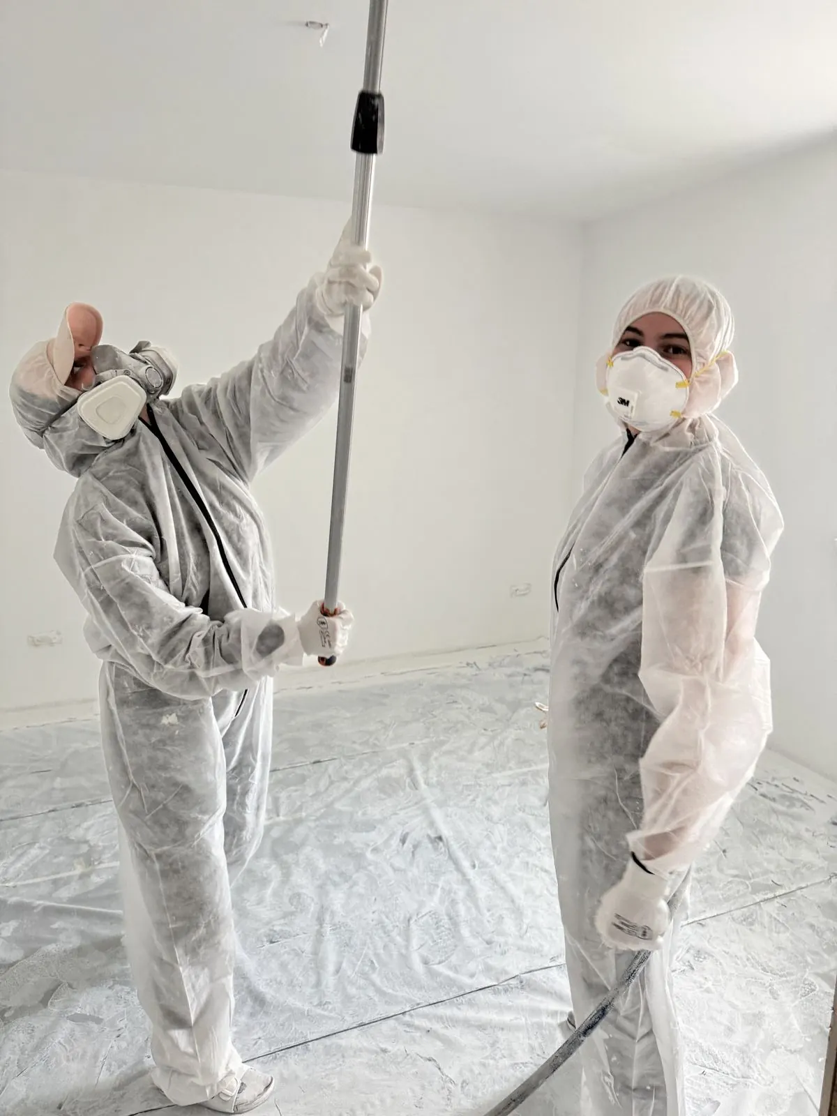 Zwei Hofbauer-Mitarbeiter in Schutzanzügen beim Airless-Spritzen einer Decke