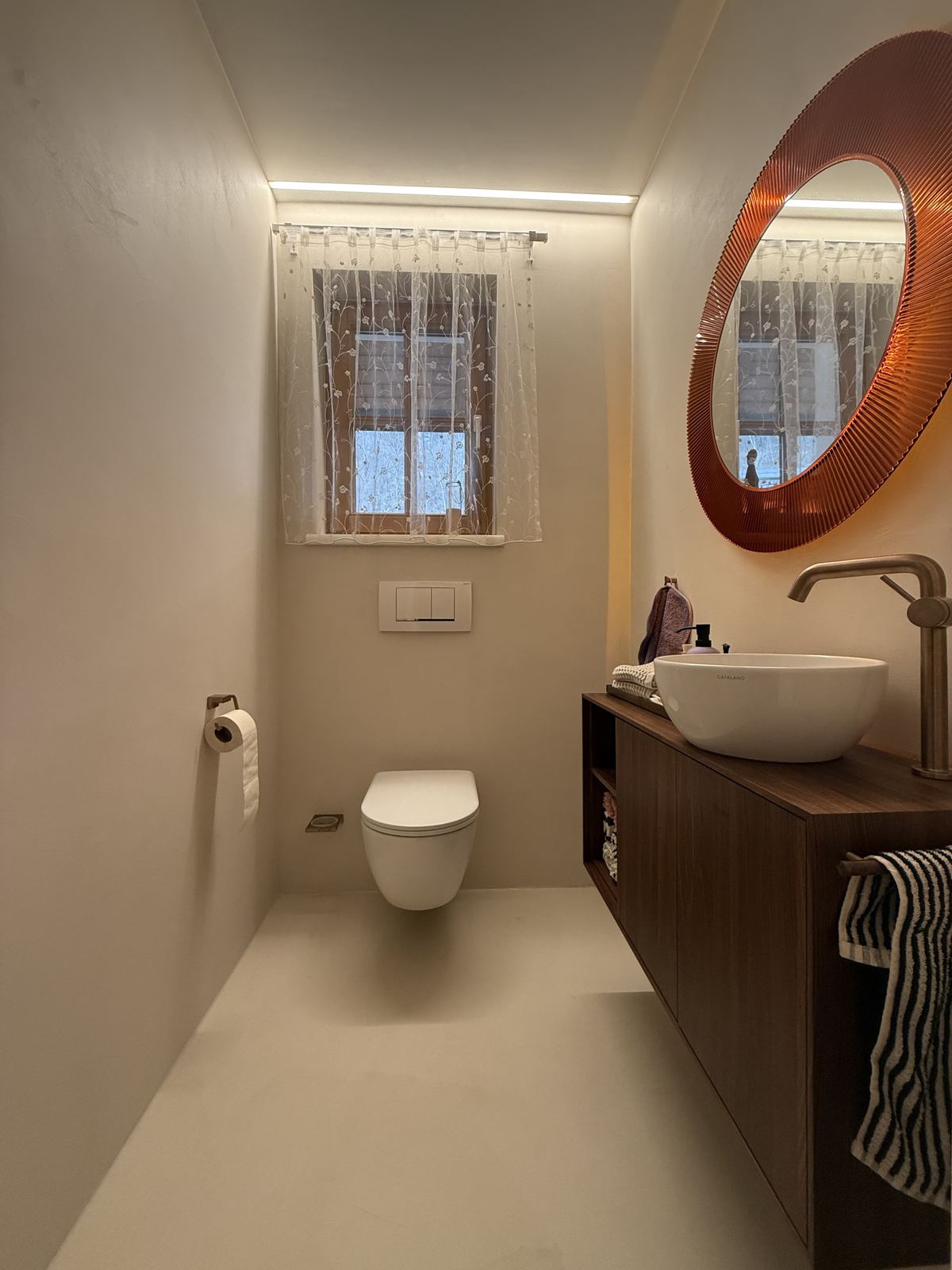 Gäste-WC mit Nussholzmöbel und fugenlosem Boden