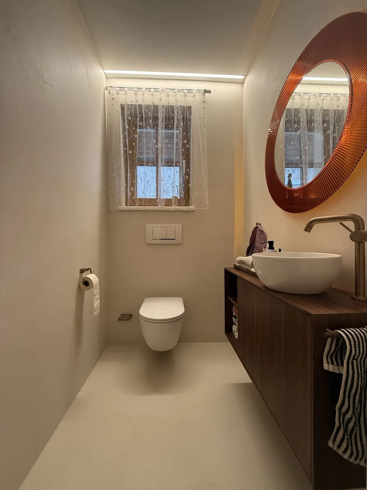 Gäste-WC mit Nussholzmöbel und fugenlosem Boden